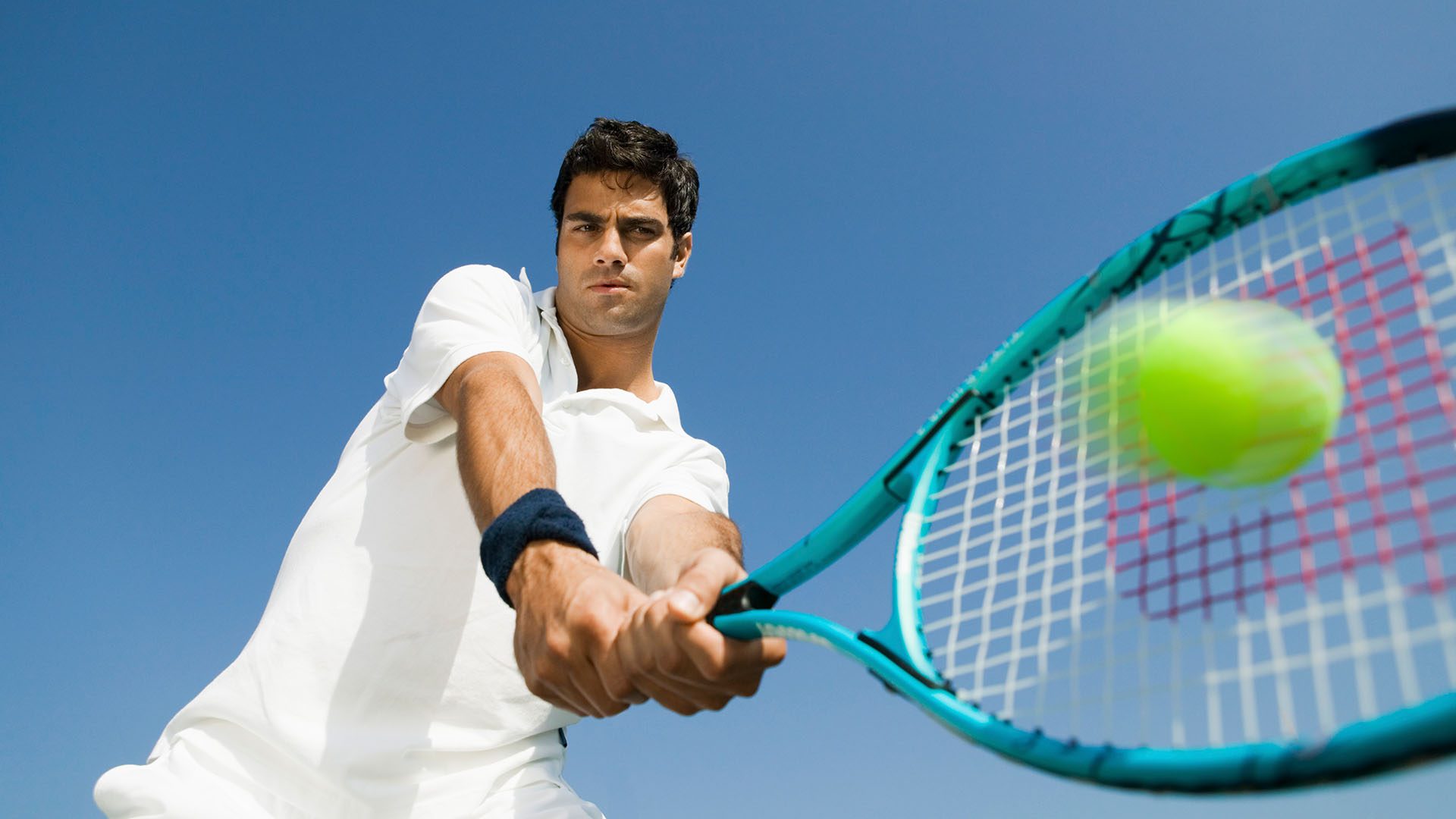 Male tennis player striking a ball